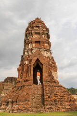A vertical shot of a tourist admiring the Wat Ratchaburana temple