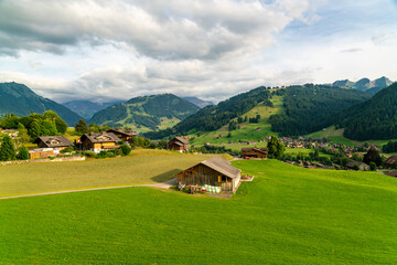 swiss countryside with green fields, houses and swiss Alps