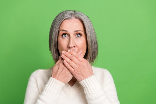 Photo portrait of grey hair old woman hands closed mouth scared silent mute speechless nervous panic isolated on green color background