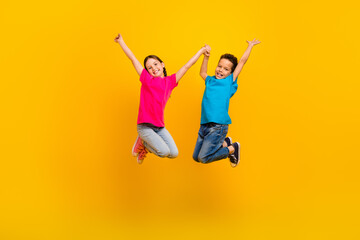 Full body portrait of two carefree cheerful schoolkids jumping hold hands have fun isolated on...