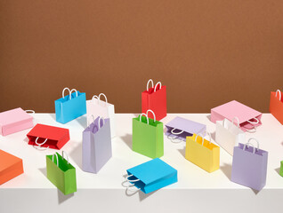 Colorful shopping bags of blue, yellow and green color are scattered on a white table. Shopping concept.