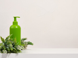 Dishwashing detergent dispenser and a green forest branch. Copy space for text.