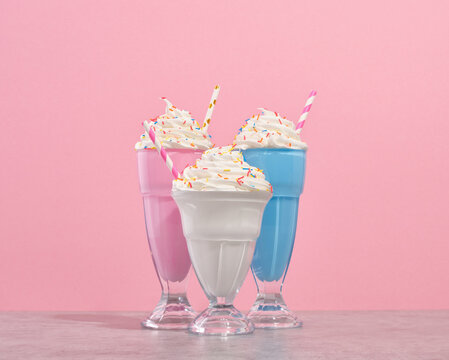 Delicious whipped cream milkshakes in glasses with colored sprinkles and colorful straws. Party and festive vacation.