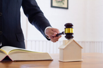 A real estate auctioneer holds a gavel in his hand to knock on a real estate auction when the final price is reached. Real estate auction concept with gavel knocking on mockup house - obrazy, fototapety, plakaty