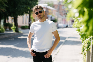 Hipster handsome male model wearing white blank t-shirt with space for your logo or design in casual urban style