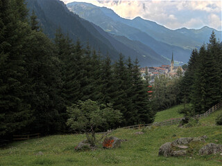 gebirgsdorf mit kirche im tal hinter einem nadelwald