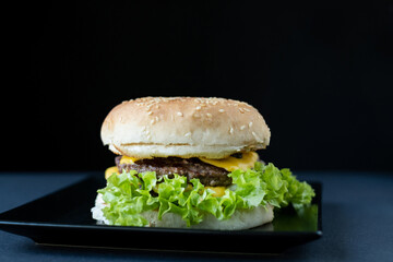 Delicious burger with meat and salad on a dark background