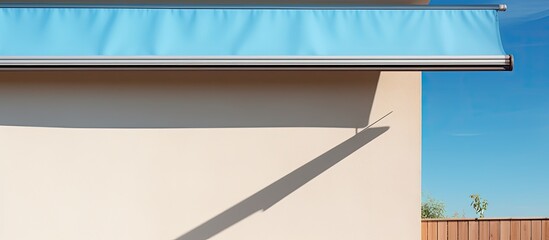 A banner with copy space hangs over a retractable awning installed on a wall, providing shade to a house window against a beautiful blue sky. - obrazy, fototapety, plakaty