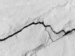 Big long tortuous crack on old plastering wall. Copy space. Black and white photo. Selective focus.