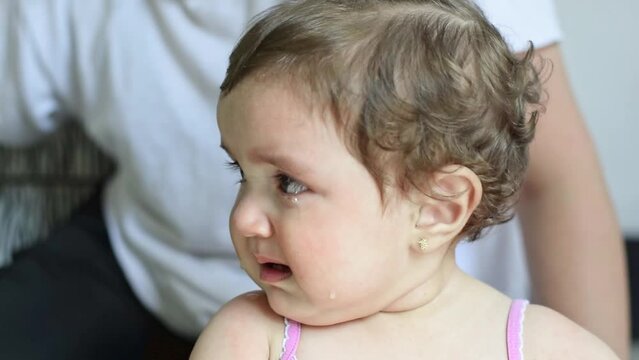 close-up of a little latina baby girl crying, while looking around her.