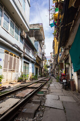 Fototapeta na wymiar Hanoi, Vietnam - May 28, 2023: Train Street in Hanoi is a narrow, bustling lane with tracks. Close knit houses, adorned with plants, are inches away from passing trains. bars and cafes line the track