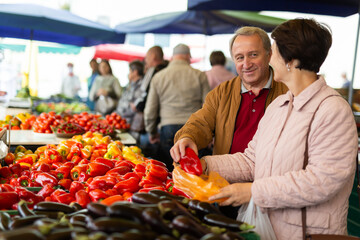 Elderly man and a woman buy pepper at an open-air market