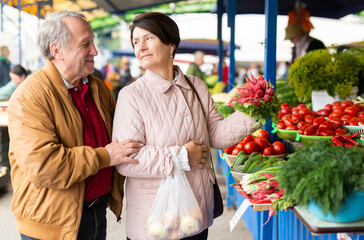  Elderly man and a woman buy radish at an open-air market