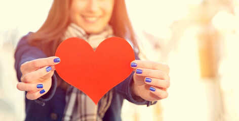 Female hands close up. Red heart in the hands. Woman and mark heart. Heart, love symbol young happy...