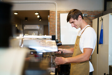 Professional caucasian coffee barista making a cup of coffee by using a modern espresso machine.