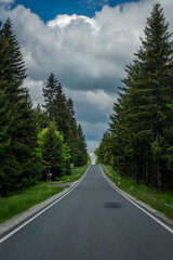 Road near Bozi Dar village in Krusne mountains with white cloudy blue sky