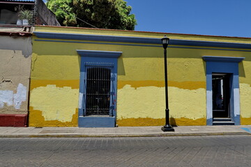 Façade de maison jaune avec graffitis effacés par une couche de peinture. Mexique.