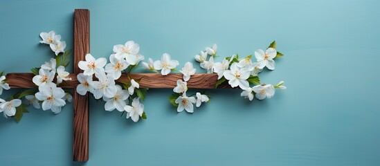 Wooden Cross adorned with Spring flowers on a blue background. Copy space available. Religious background representing Church holidays in Christianity such as Easter, Palm Sunday, Christening, and