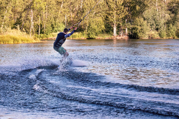 Wakeboarding on the sea on summer day in life jacket. Soft focus. Action blur.