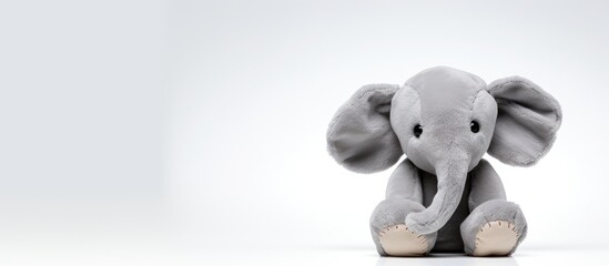 A Soft Toy Elephant is sitting down alone on a white background with empty space for text.