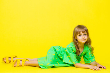 Girl kid in green dress lying on floor, relaxing, chill, enjoying, looking at camera with smile....