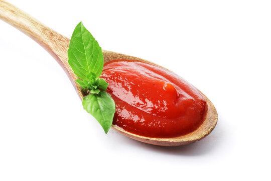 Wooden spoon full of tomato sauce with fresh basil isolated on white background.