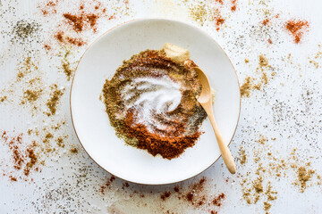 An abstract view of a plate of various spices partially mixed with spices around