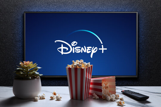 Disney plus logo on TV with popcorn boxes, reomote control and home plant. Astana, Kazakhstan - July 21, 2023.