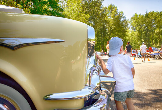 Little boy with hat views vintage cars at classic automobile exhibition. 