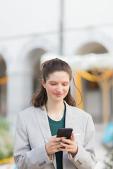 Fototapeta premium Smiling young woman using her cell phone in city