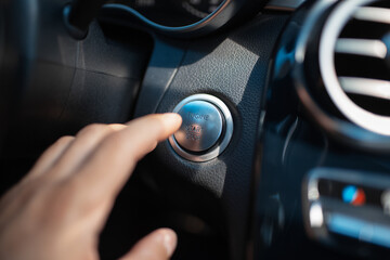 A male finger press the car button of engine start stop.