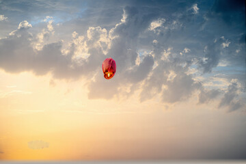 orange sky lantern floating in the middle of grey sky on the festival of independence day makar...