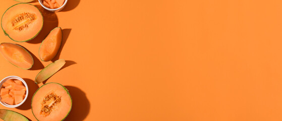 Pieces of sweet ripe melons on orange background with space for text, top view