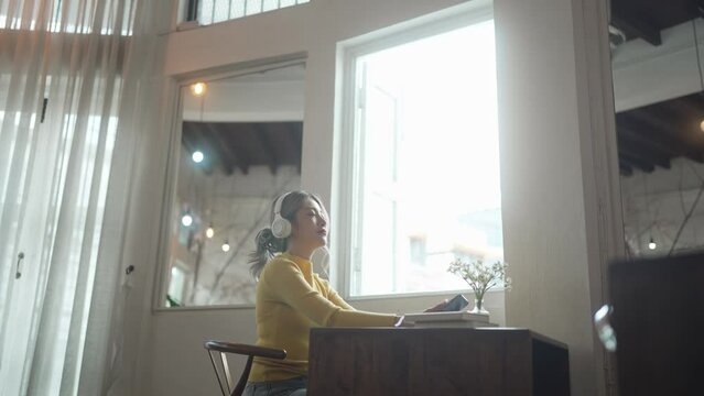 Young asian woman wearing headphone listening music at her home..