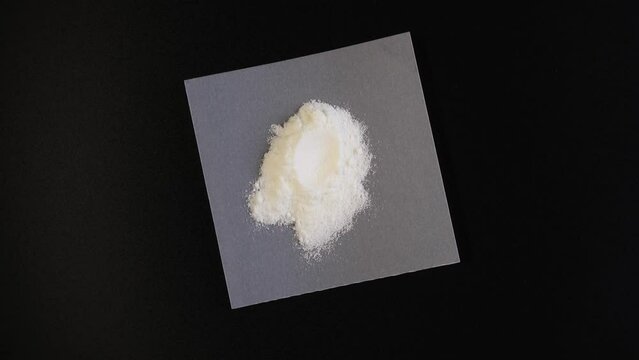 Pile of Carrageenan Gum Powder on dark background, top view. Food additive E407 or E407a. 4K Video, Rotating. Carrageenan used in production of dairy products, milkshakes, ice cream, confectionery.