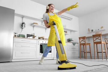 Young woman with headphones hoovering carpet in kitchen