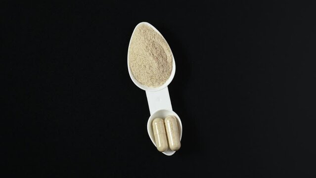 Psyllium husk powder vs Psyllium husk capsules in measuring spoon. 4K Video, Rotating. Comparison of different forms of natural dietary supplements for health.