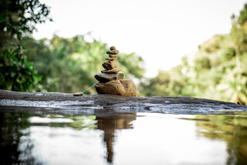 Serenity in Balance: Stacked Stones by a Tranquil Waterfall