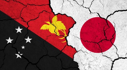 Flags of Papua New Guinea and Japan on cracked surface - politics, relationship concept