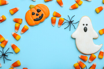 Frame made of tasty Halloween candy corns, cookies and spiders on blue background