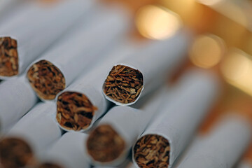 Many cigarettes in colorful background close up of a roll tobacco in paper with filter tube no...