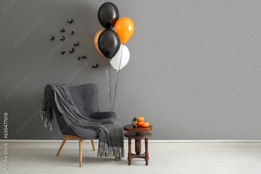 Wall mural armchair, table, halloween balloons and bats hanging on grey wall in room