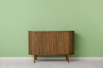 Wooden chest of drawers near green wall in room