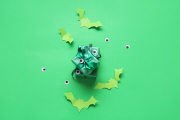 Obraz premium Green halloween gift boxes with googly eyes and paper bats on a bright green background, spooky holiday celebration, this festive composition represents a spooky holiday celebration and october party