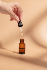 female hand with Dropper of essential oil, aromatherapy essence, beuty serum or medicinal liquid on...
