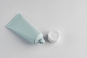 Top view of green squezze tube with open cap on white background. Cosmetics mockup.