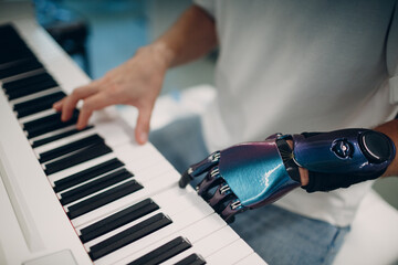 Cropped image of person with prosthetic hand playing piano