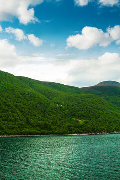 Green mountain beside lake under blue sky