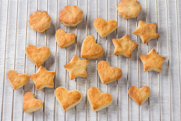 Freshly baked cottage cheese cookies in the shape of stars and hearts on a steel grid, top view....