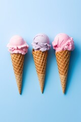 Ice cream scoops in waffle cones on blue background, top view